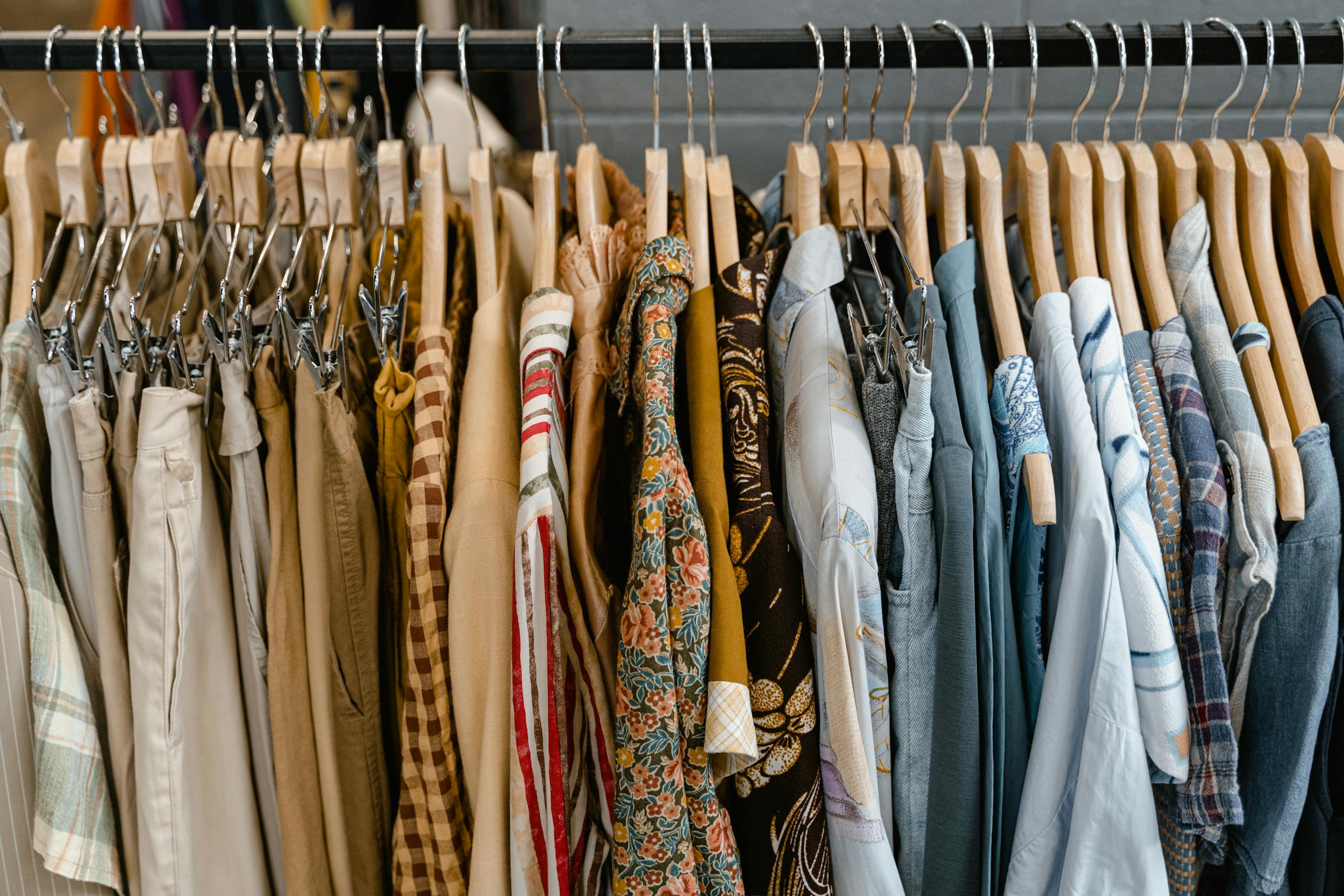 A diverse selection of clothing items arranged on hangers in a store setting, showcasing fashion trends.